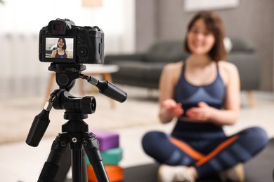 Photo of Happy sports blogger recording fitness lesson at home, focus on camera