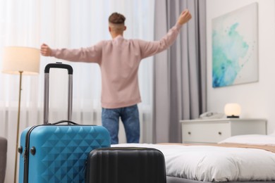 Guest stretching in stylish hotel room, focus on suitcases