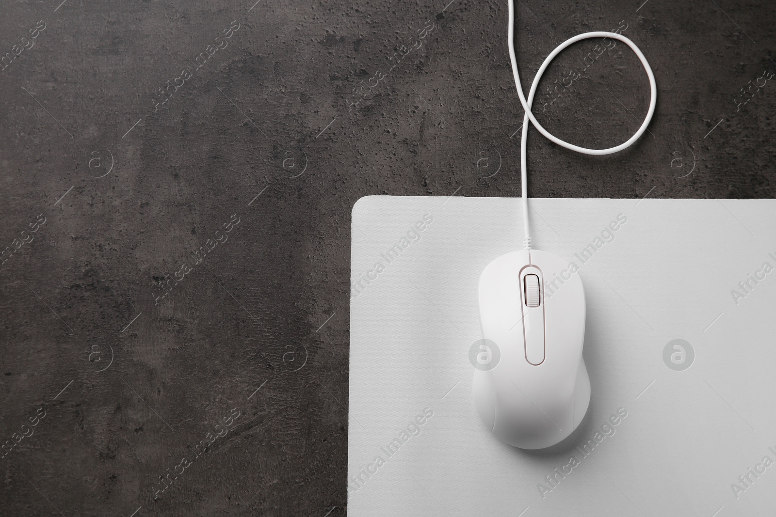 Photo of Wired mouse with mousepad on black textured table, top view. Space for text