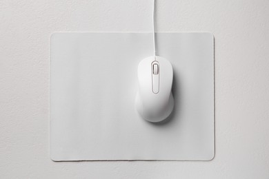 Wired mouse with mousepad on light textured table, top view