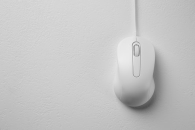 Wired mouse on light textured table, top view. Space for text