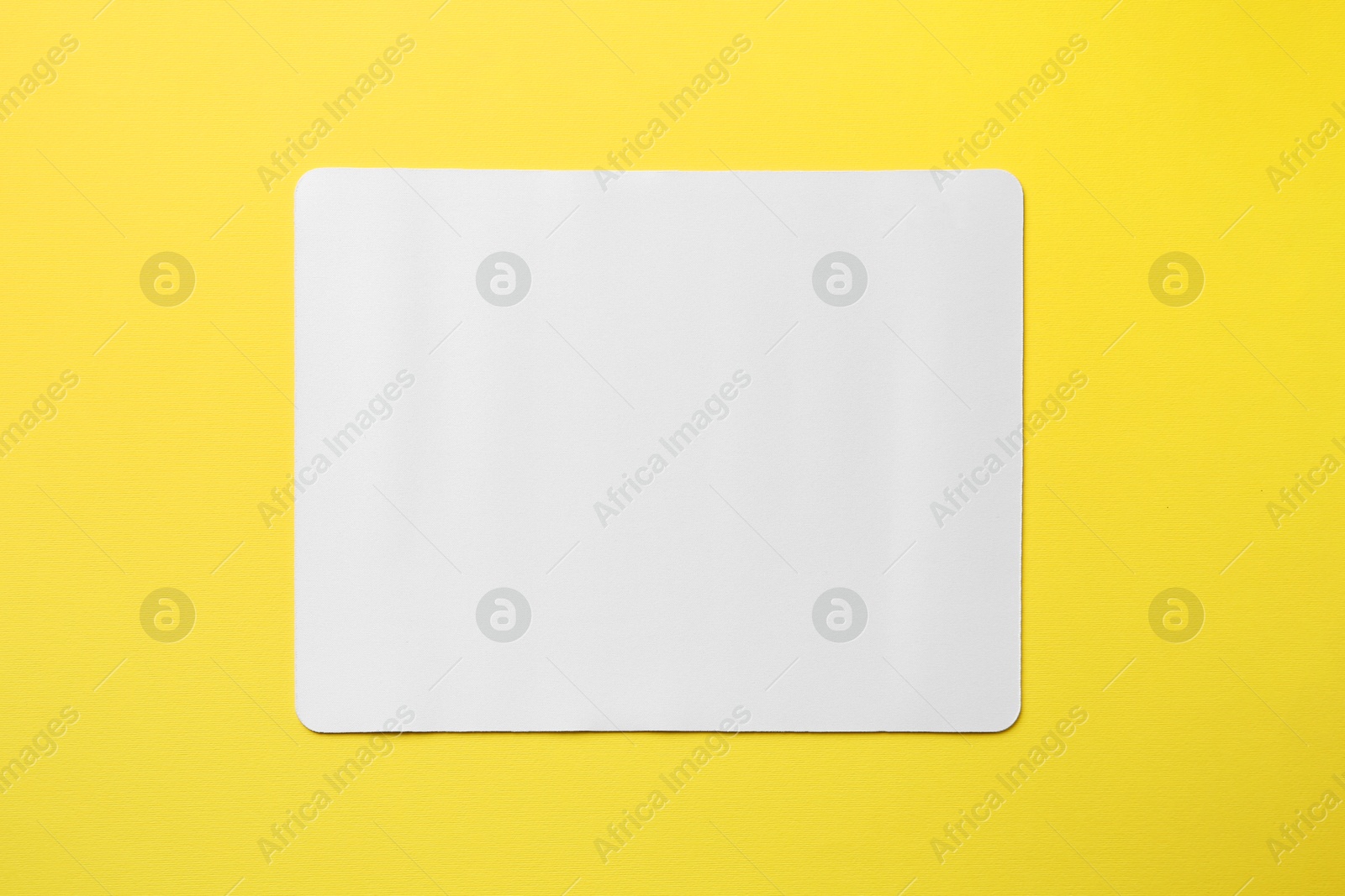 Photo of One white mouse pad on yellow background, top view. Space for text