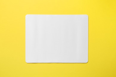 Photo of One white mouse pad on yellow background, top view. Space for text