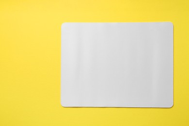 Photo of One white mouse pad on yellow background, top view. Space for text