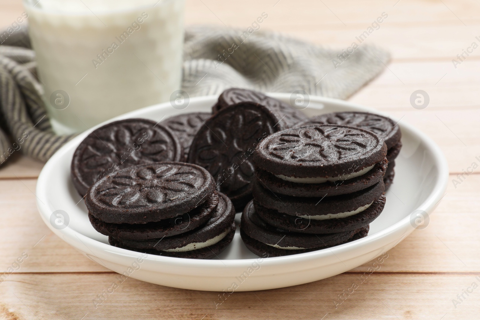 Photo of Plate with tasty sandwich cookies on light wooden table, closeup