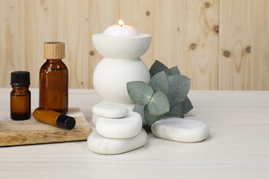 Photo of Different aromatherapy products and burning candle on white wooden table
