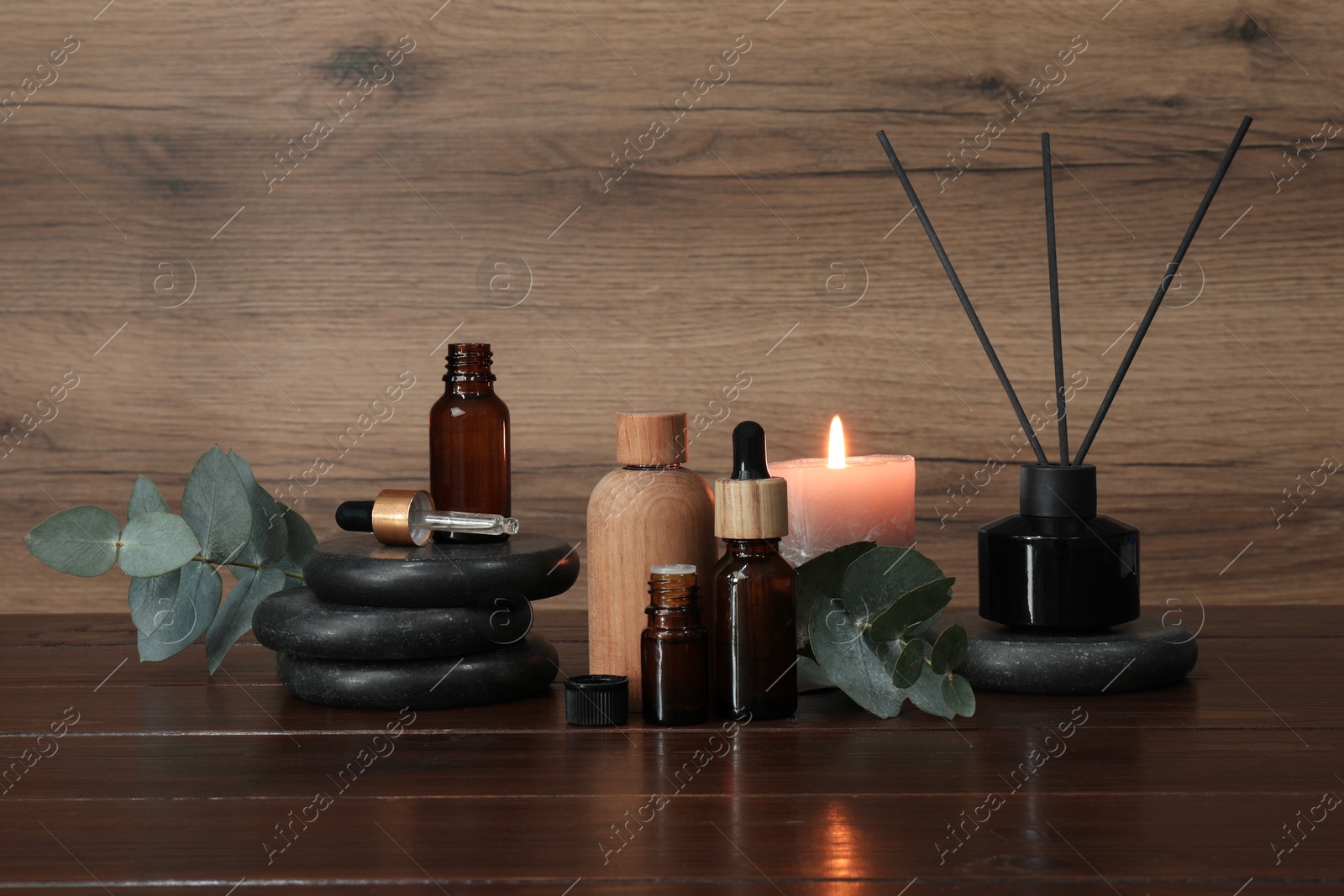 Photo of Aromatherapy products and burning candle on wooden table