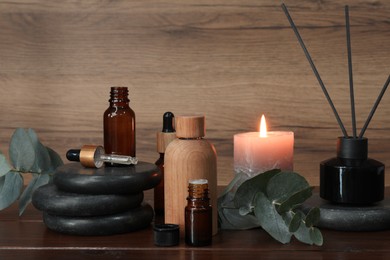 Photo of Aromatherapy products and burning candle on wooden table