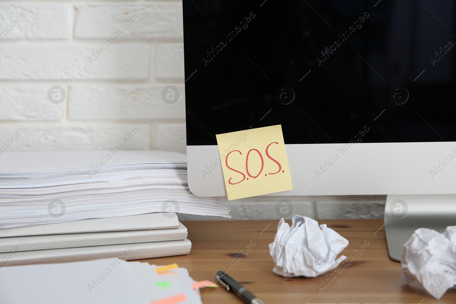 Photo of Note with word SOS and stationery on computer at workplace