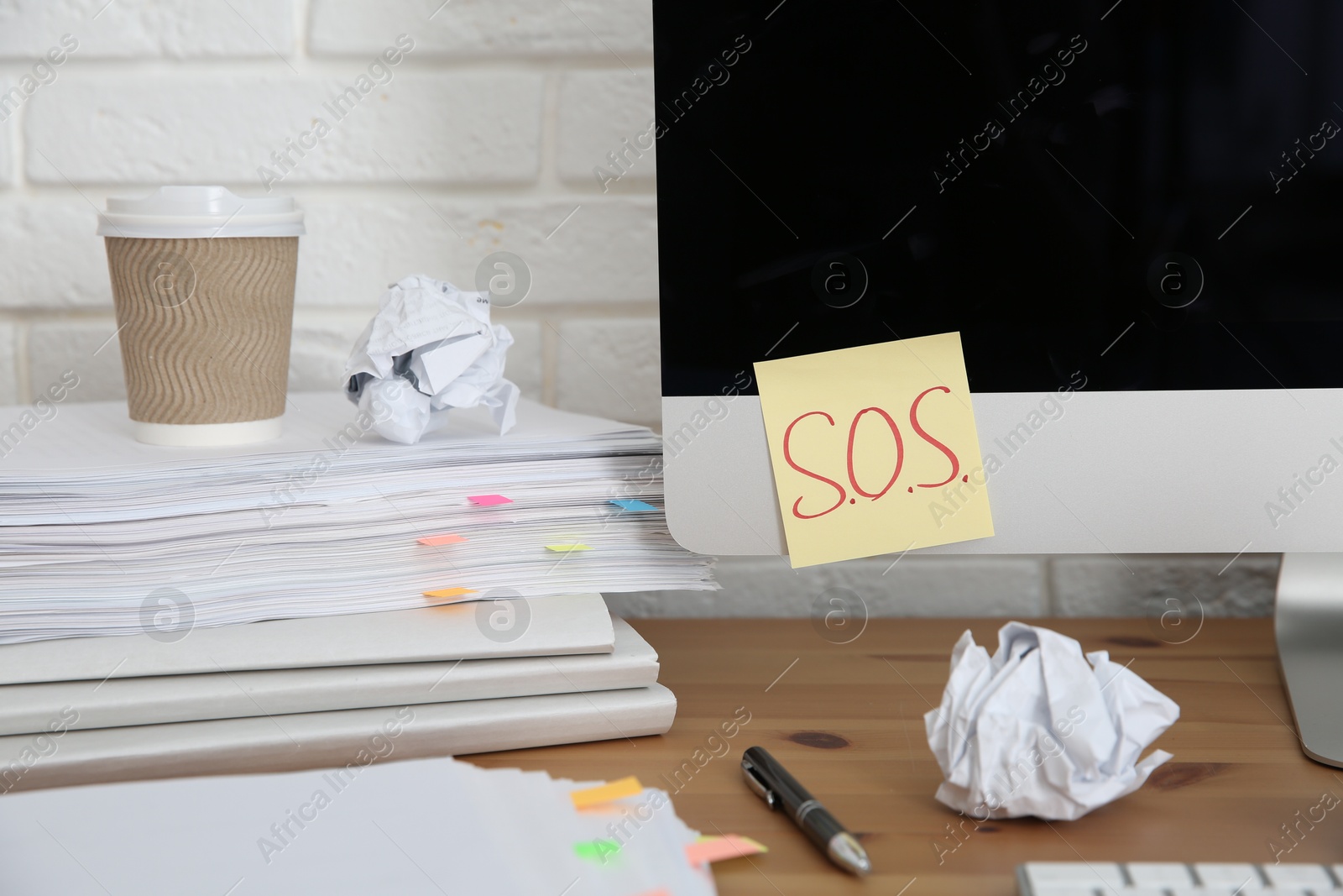 Photo of Note with word SOS and stationery on computer at workplace