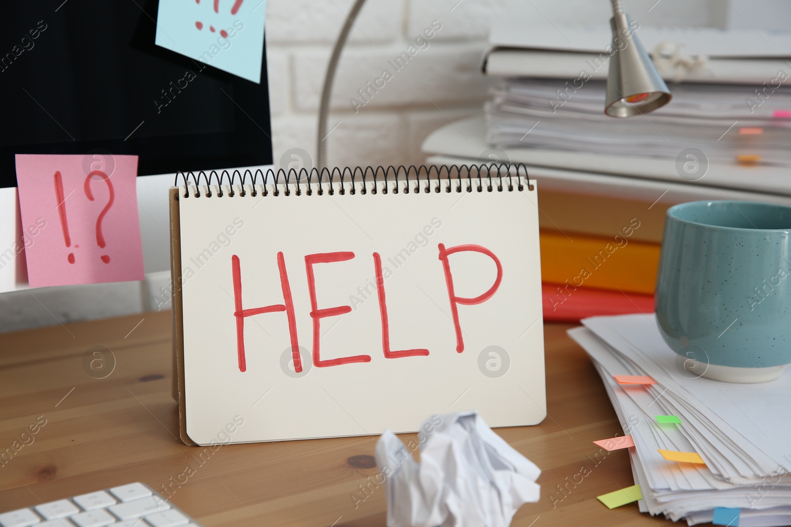 Photo of Notebook with word Help, computer and stationery on wooden table at workplace