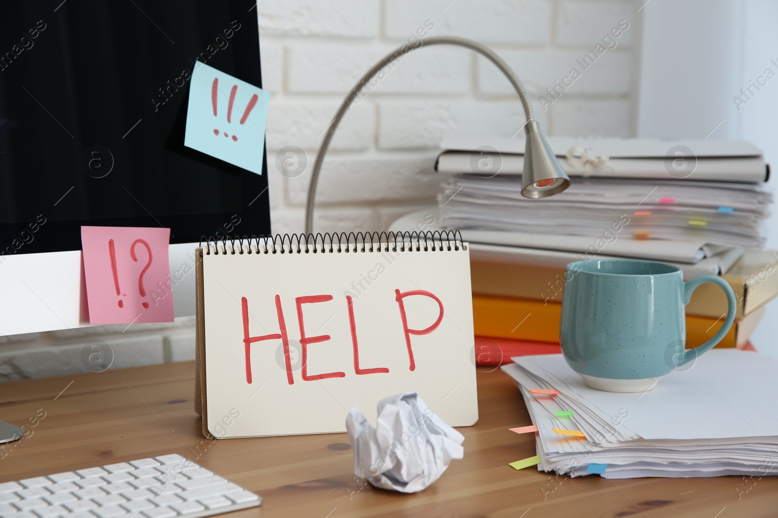 Photo of Notebook with word Help, computer and stationery on wooden table at workplace