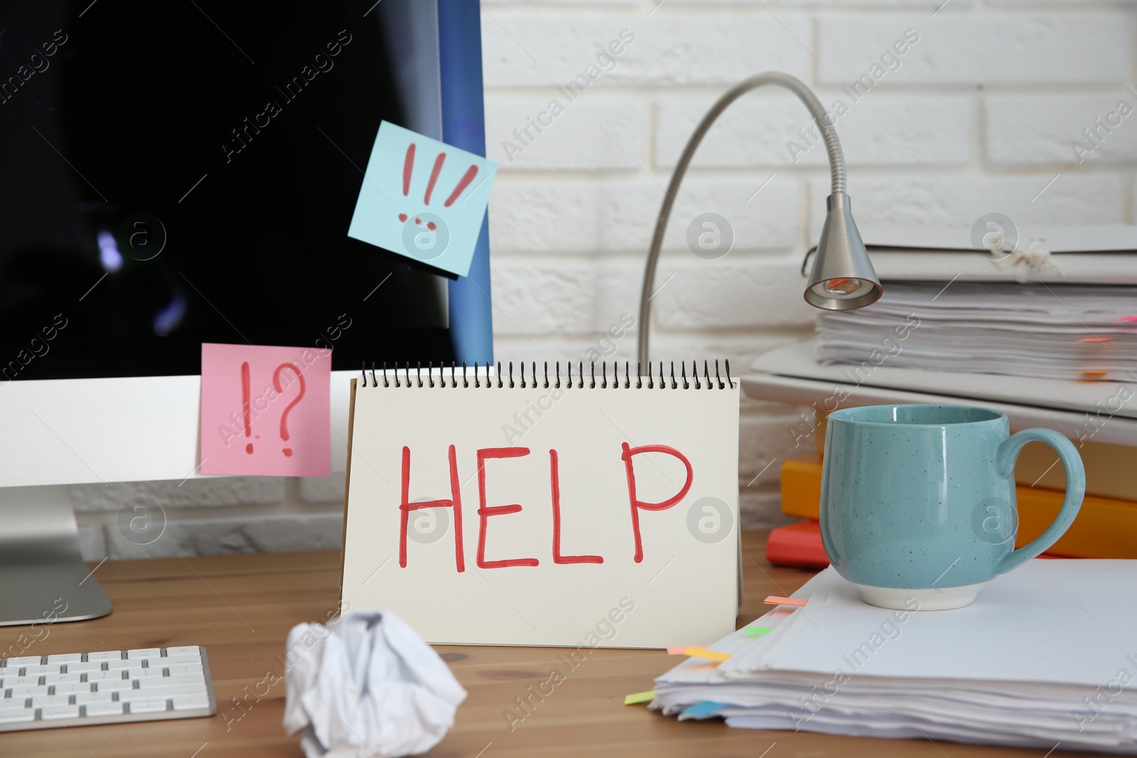 Photo of Notebook with word Help, computer and stationery on wooden table at workplace