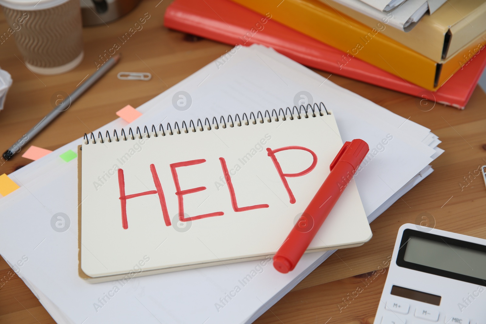 Photo of Notebook with word Help and stationery on wooden table at workplace