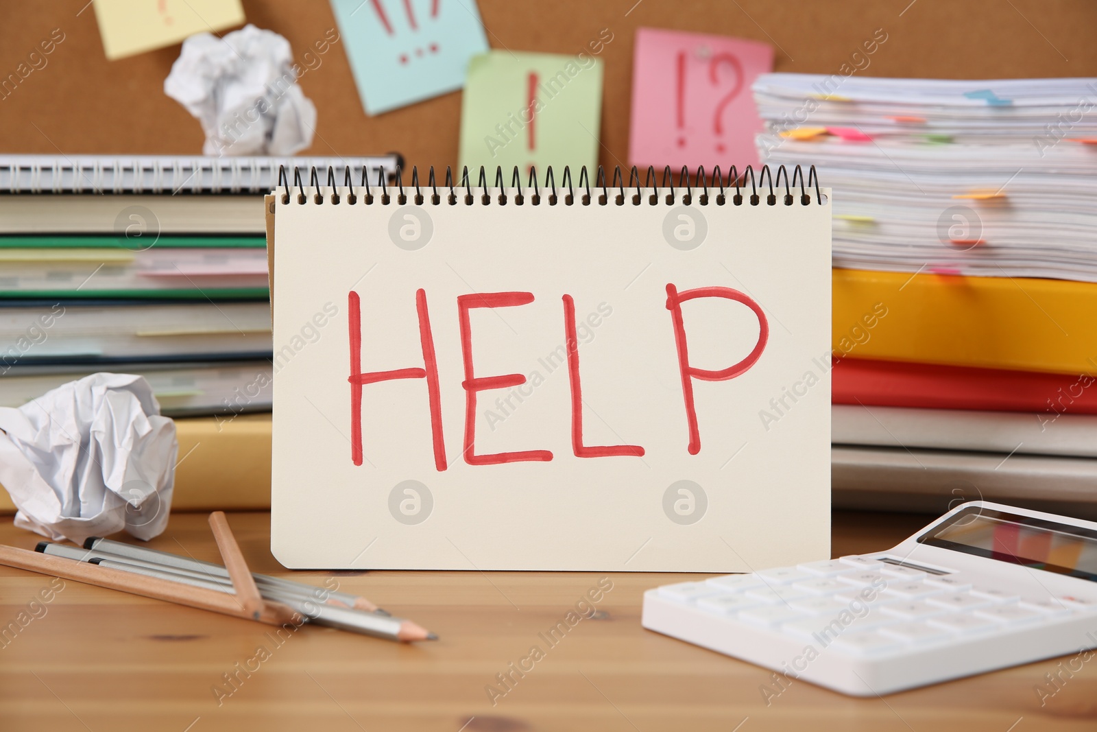 Photo of Notebook with word Help and stationery on wooden table at workplace