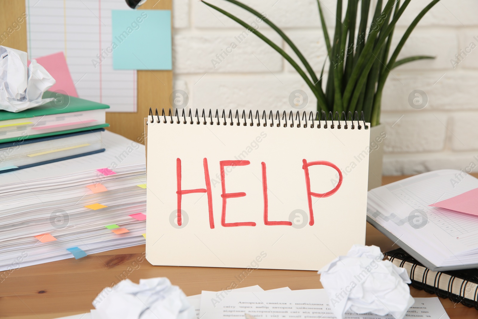 Photo of Notebook with word Help and stationery on wooden table at workplace