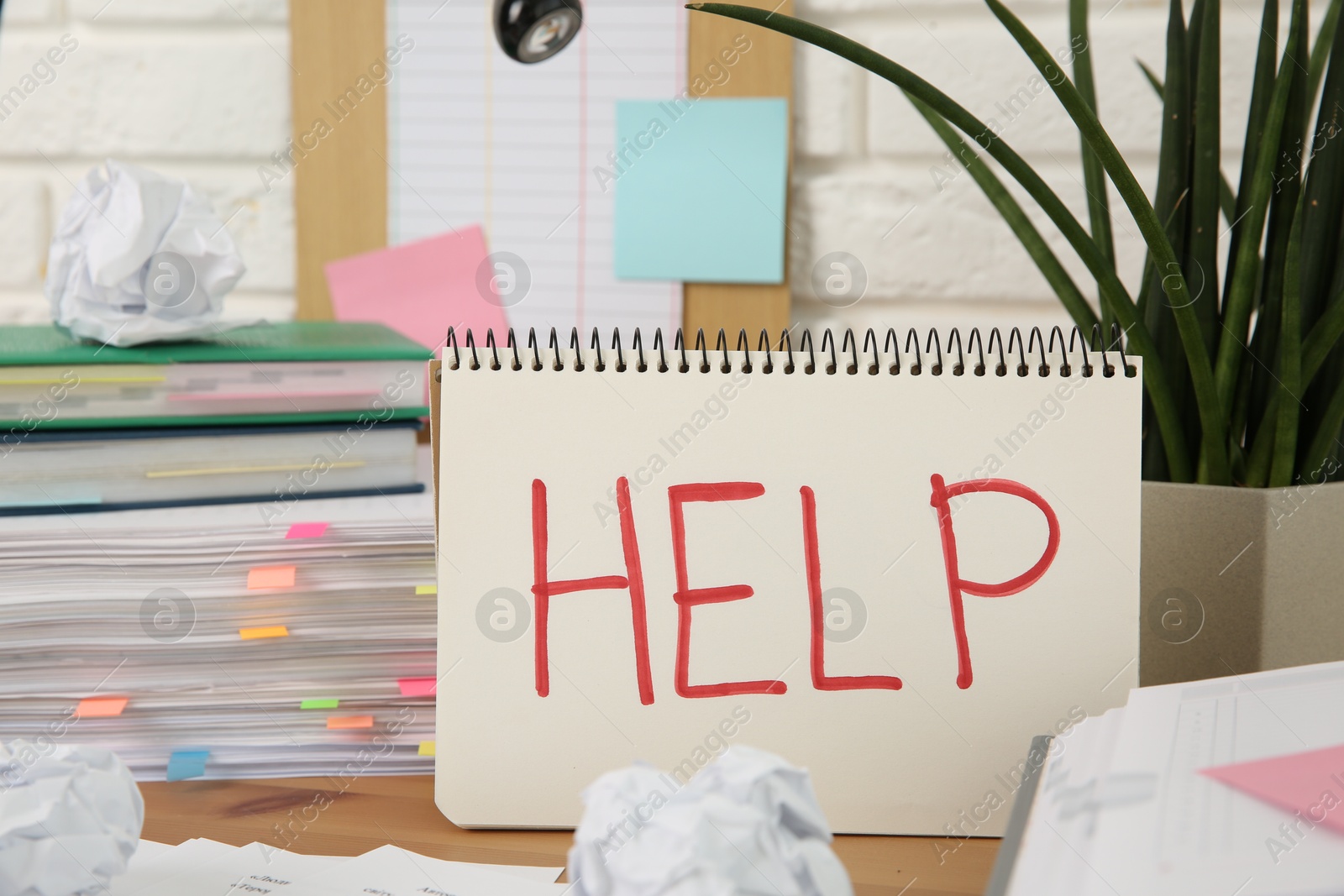 Photo of Notebook with word Help and stationery on wooden table at workplace