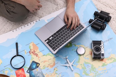 Travel blogger using laptop and map for planning trip, top view