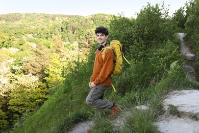 Photo of Travel blogger with headphones and backpack outdoors