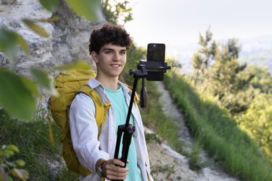 Photo of Travel blogger with smartphone and tripod recording video outdoors