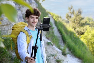 Travel blogger with smartphone and tripod recording video outdoors, space for text