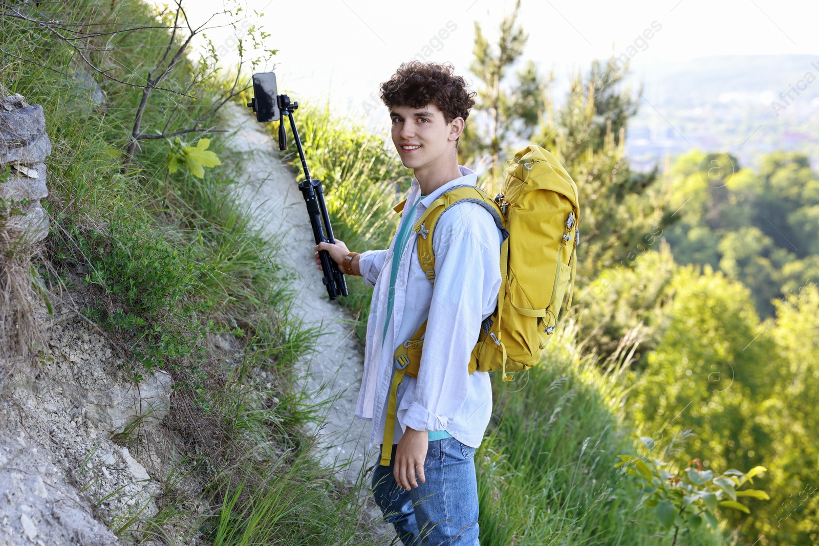 Photo of Travel blogger with smartphone and tripod recording video outdoors