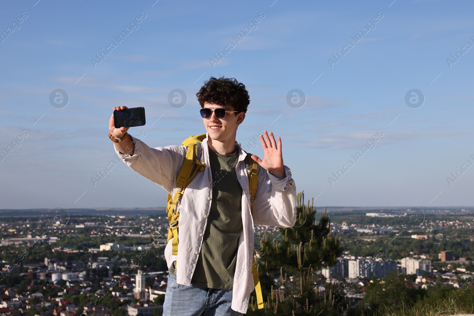 Photo of Travel blogger in sunglasses with smartphone streaming outdoors