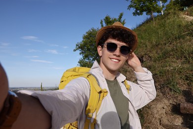 Photo of Travel blogger in sunglasses takIng selfie outdoors