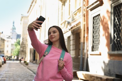 Photo of Travel blogger takIng selfie with smartphone on city street