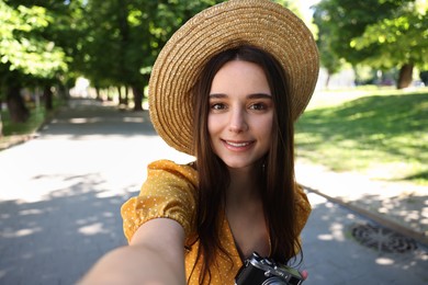 Travel blogger with vintage camera takIng selfie outdoors