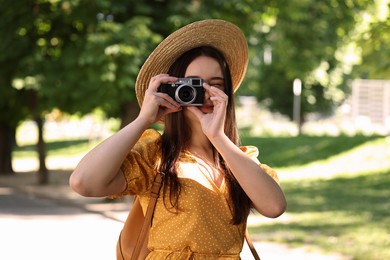 Travel blogger takIng picture with vintage camera in park