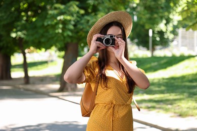 Photo of Travel blogger takIng picture with vintage camera in park