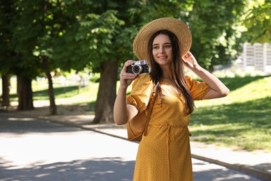 Travel blogger takIng picture with vintage camera in park