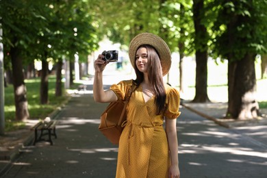 Photo of Travel blogger takIng picture with vintage camera outdoors