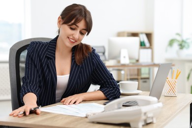 Smiling secretary doing paperwork at table in office