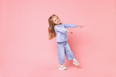 Cute little girl dancing on pink background