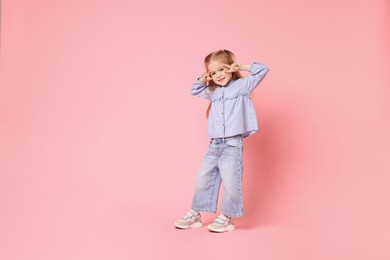 Cute little girl dancing on pink background, space for text