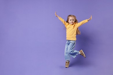 Cute little girl dancing on purple background, space for text