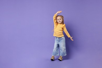 Cute little girl dancing on purple background, space for text