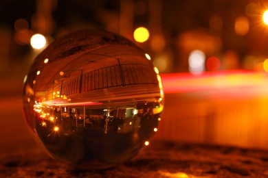 Beautiful city street, overturned reflection. Crystal ball at night, closeup. Space for text