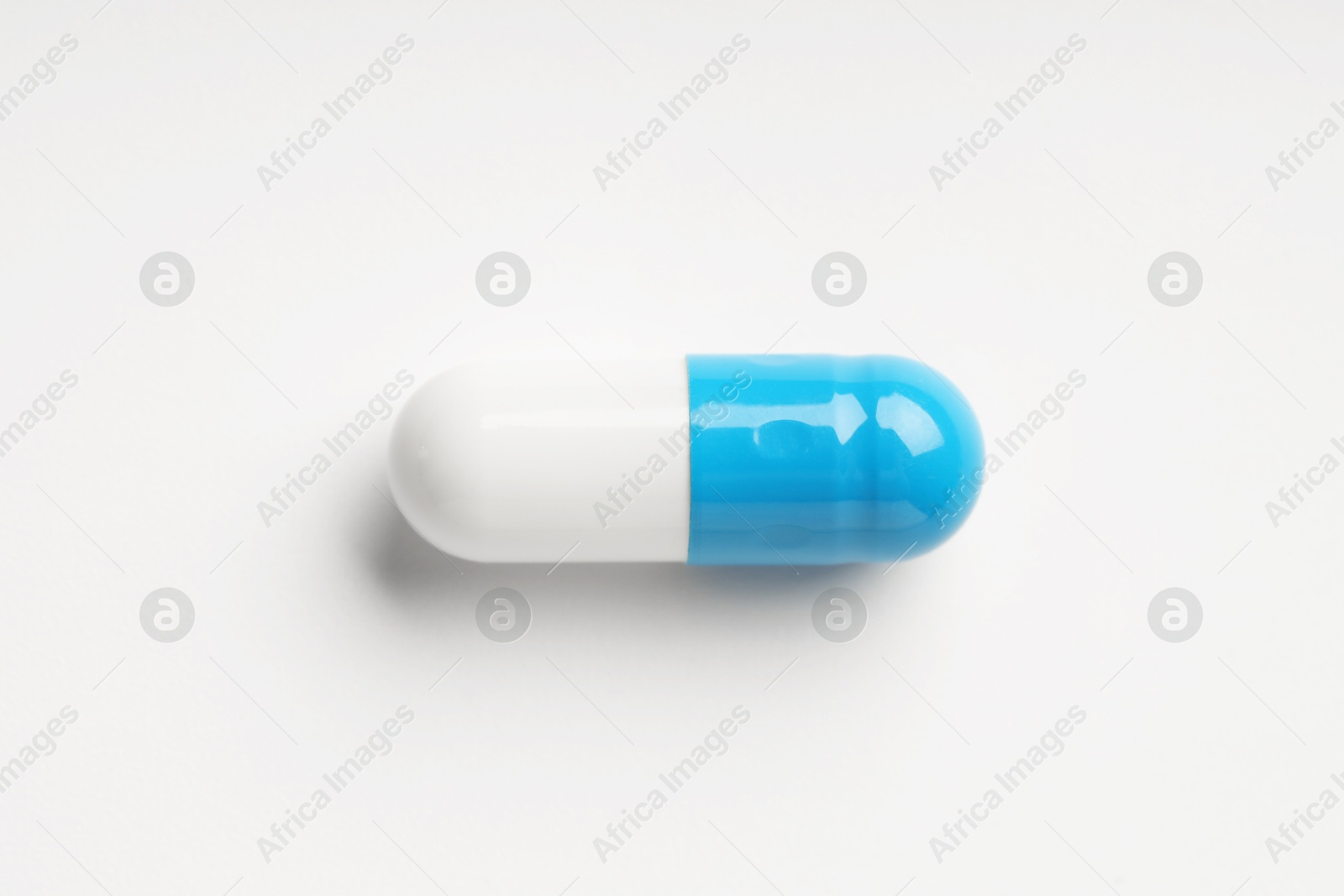 Photo of One antibiotic pill on white background, top view