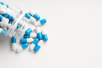 Antibiotic pills and bottle on white background, top view. Space for text