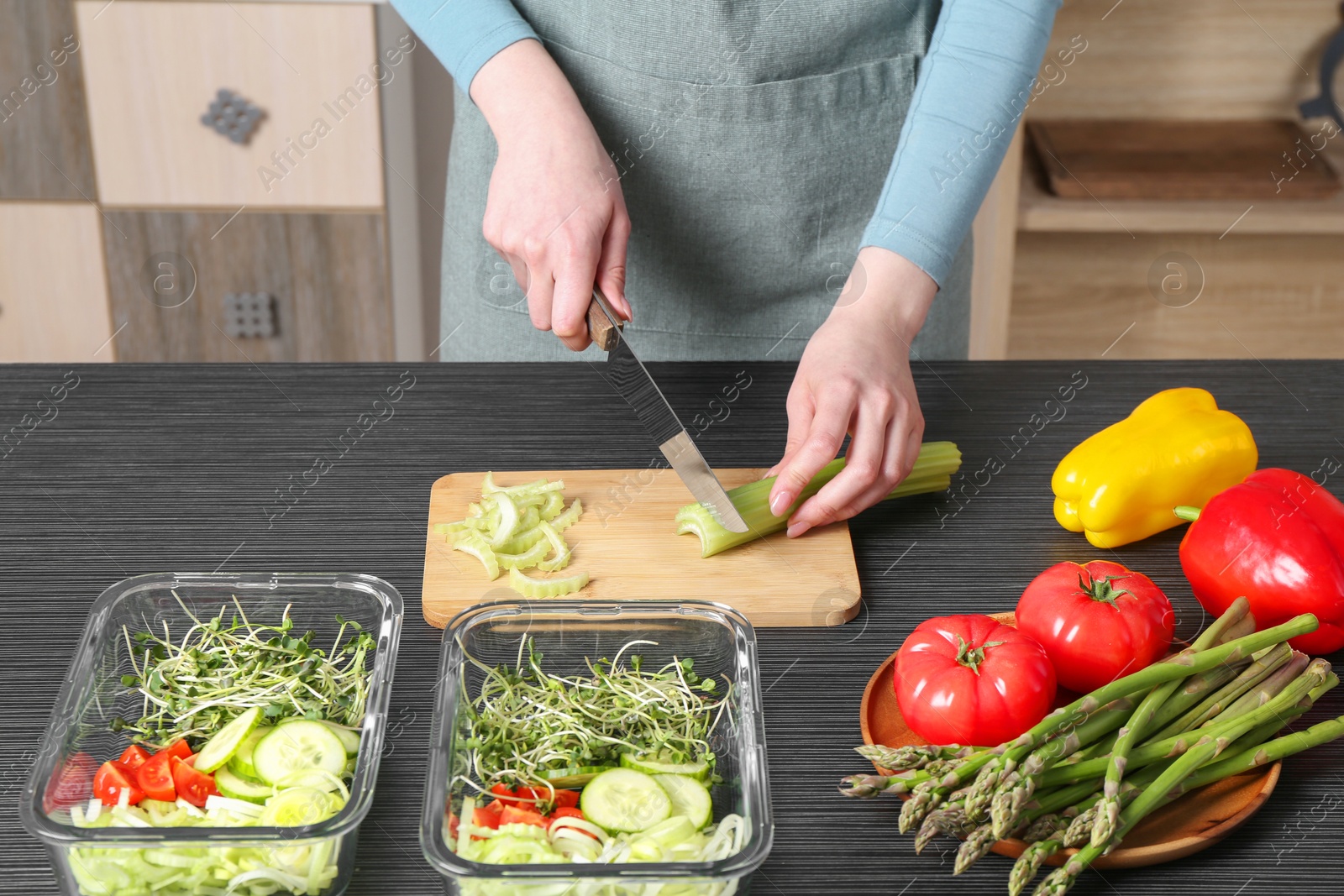 Photo of Healthy food. Woman cutting celery at black wooden table, closeup