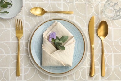 Stylish setting with cutlery, plates, napkin, glass and floral decor on table, flat lay