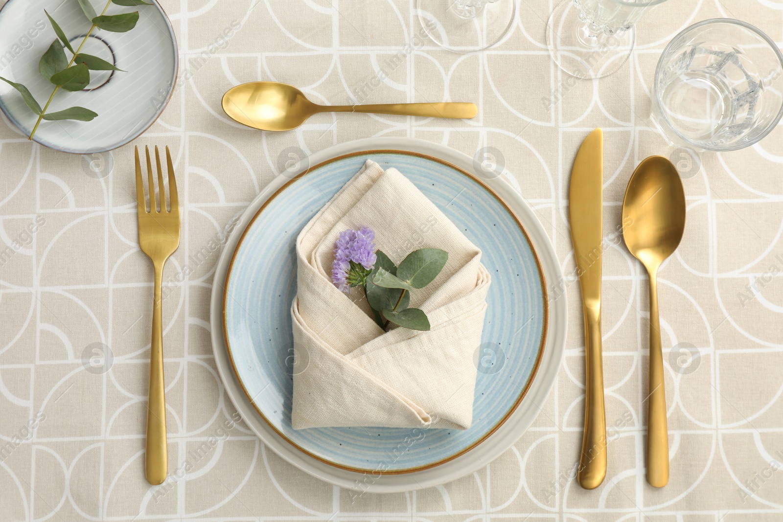 Photo of Stylish setting with cutlery, plates, napkin, glass and floral decor on table, flat lay