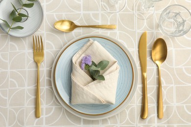 Photo of Stylish setting with cutlery, plates, napkin, glass and floral decor on table, flat lay