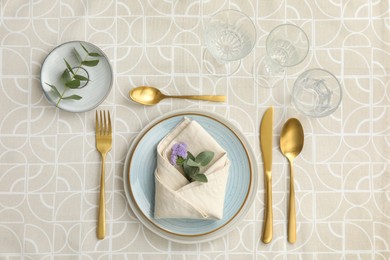 Photo of Stylish setting with cutlery, plates, napkin, glasses and floral decor on table, flat lay