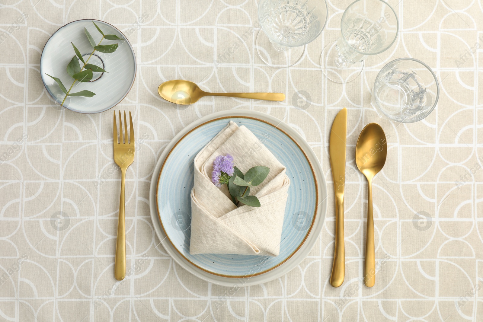 Photo of Stylish setting with cutlery, plates, napkin, glasses and floral decor on table, flat lay