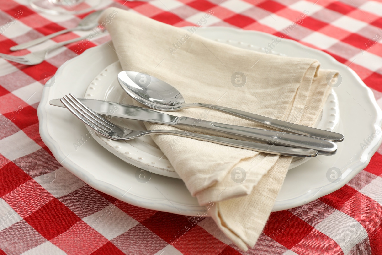 Photo of Stylish setting with cutlery, plates and napkin on table, closeup