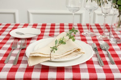 Photo of Stylish setting with cutlery, plates, napkin, glasses and floral decor on table